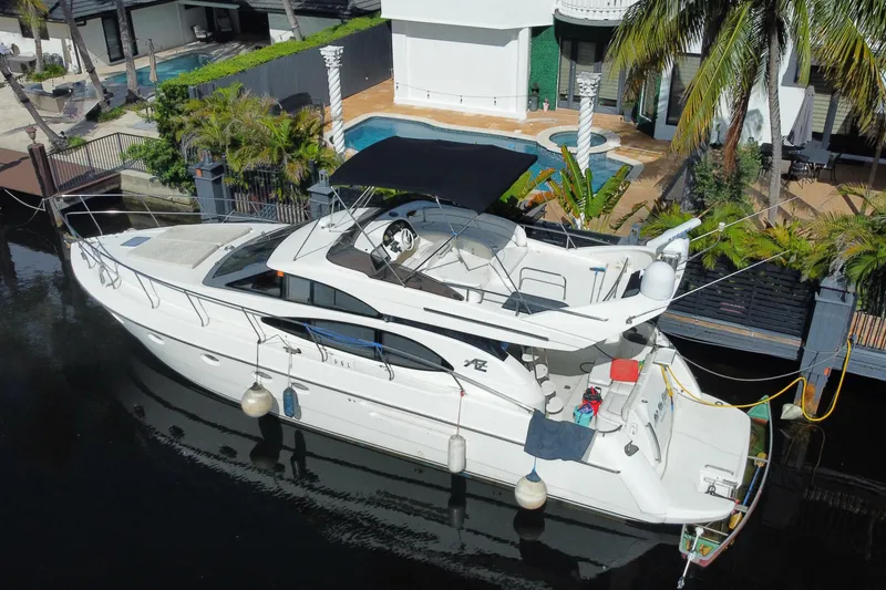 Slide: The Image of 1998 Azimut 52 yacht docked by a luxurious waterfront property with palm trees. - 21