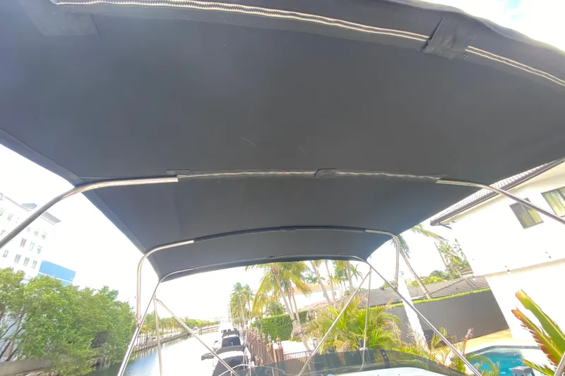 Slide: The Image of Bimini top of 1998 Azimut 52 yacht, docked near waterfront homes and palm trees. - 51