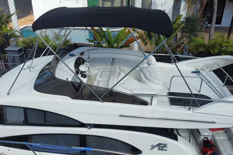 Slide: The Image of 1998 Azimut 52 yacht with canopy, docked near a poolside villa. - 54