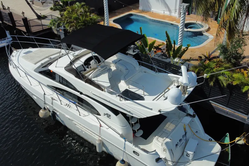 Slide: The Image of Azimut 52 yacht from 1998 docked near a luxurious poolside setting. - 59
