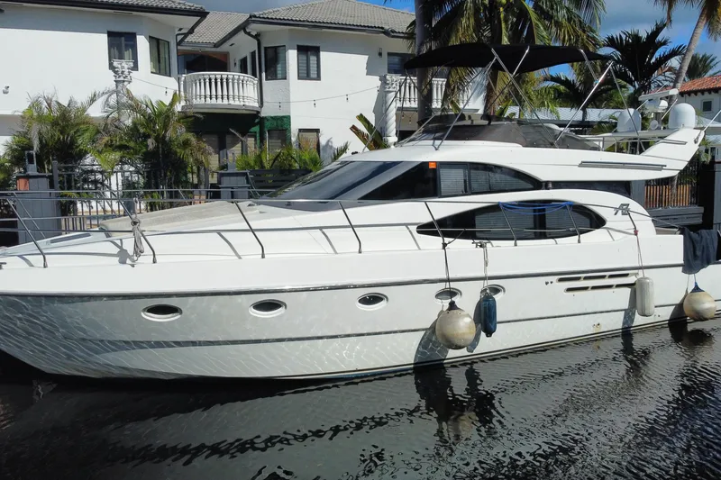 Slide: The Image of 1998 Azimut 52 yacht docked near waterfront homes, surrounded by palm trees. - 60