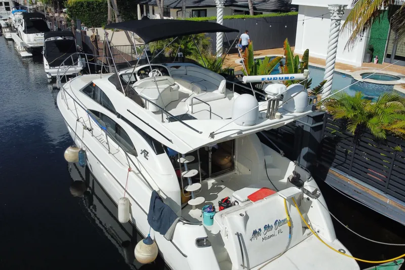 Slide: The Image of 1998 Azimut 52 yacht docked in a canal, featuring a spacious deck and modern amenities. - 64