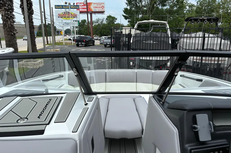 Slide: The Image of 2026 Moomba Tykon boat interior with windshield and seating, parked at a dealership. - 30