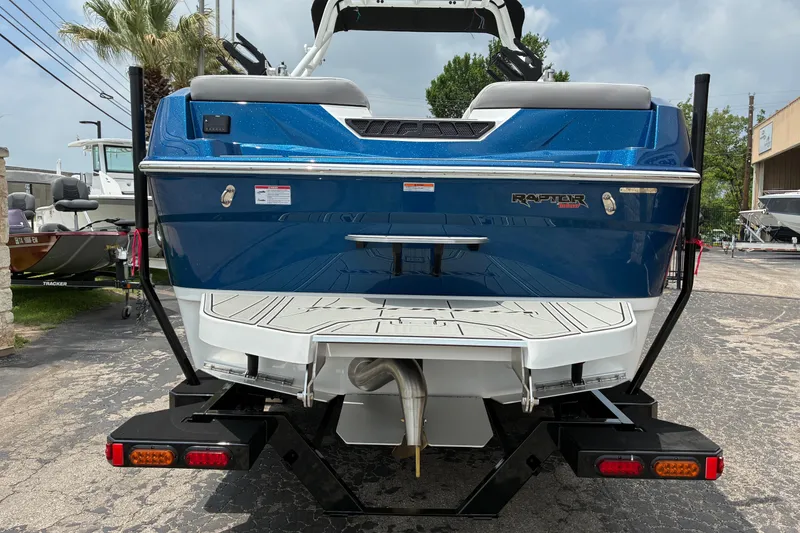 Slide: The Image of 2026 Moomba Tykon boat rear view, featuring blue exterior and Raptor engine branding. - 7
