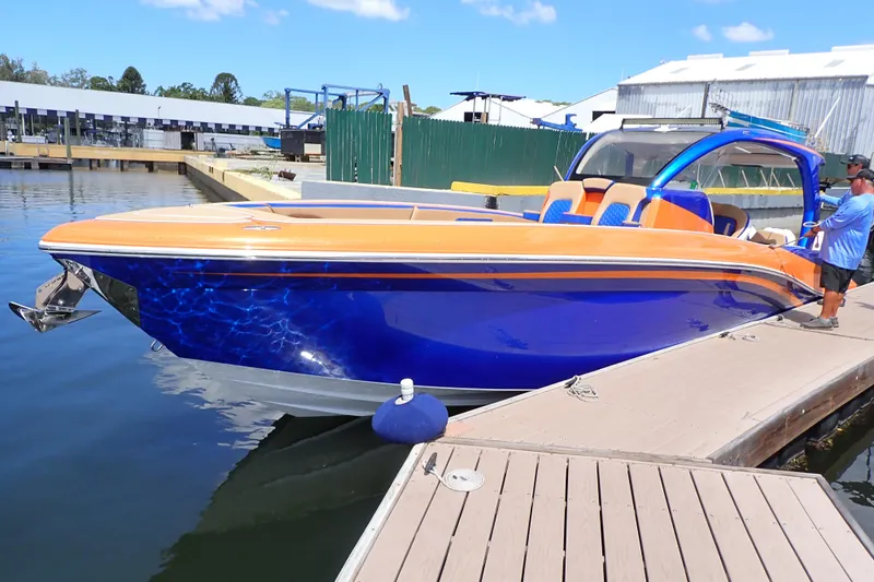 Slide: The Image of 2022 Deep Impact 369 Sport boat docked, featuring vibrant orange and blue design. - 109
