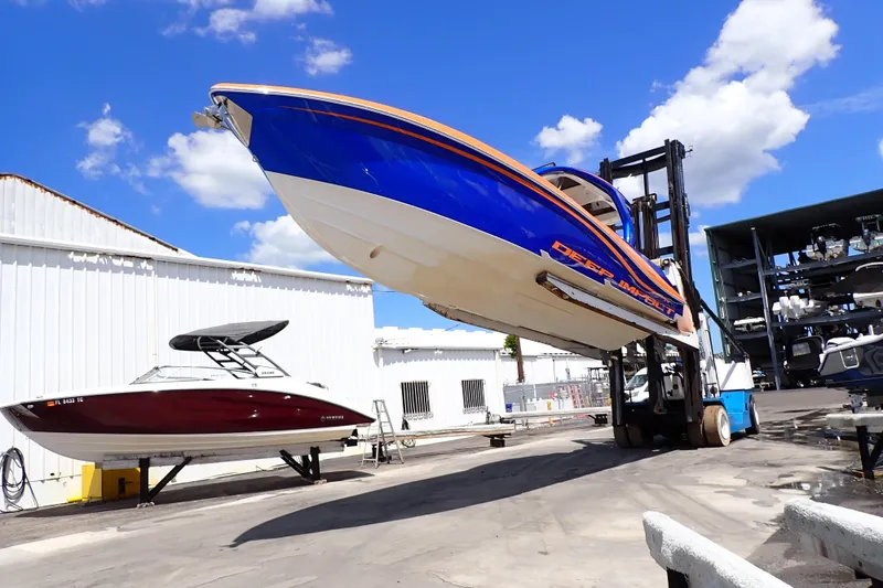Slide: The Image of 2022 Deep Impact 369 Sport boat lifted by forklift at marina under blue sky. - 111