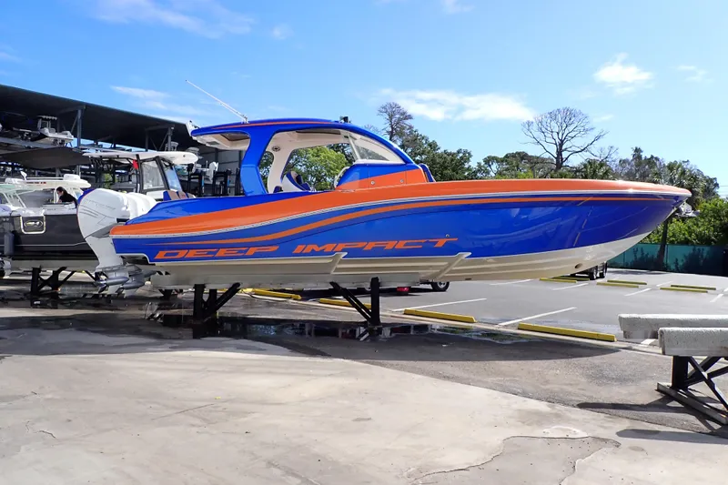 Slide: The Image of 2022 Deep Impact 369 Sport boat in vibrant blue and orange, displayed on a stand. - 4