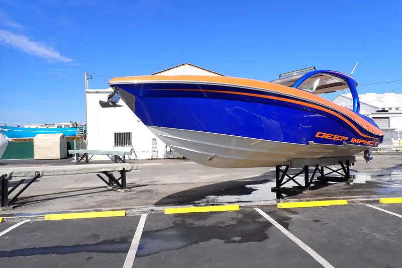 Slide: The Image of 2022 Deep Impact 369 Sport boat in vibrant blue and orange, displayed on stands. - 5