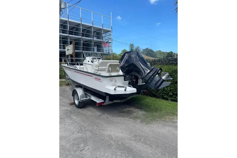 Slide: The Image of 2022 Boston Whaler 170 Montauk boat on trailer, parked outdoors with clear sky. - 12