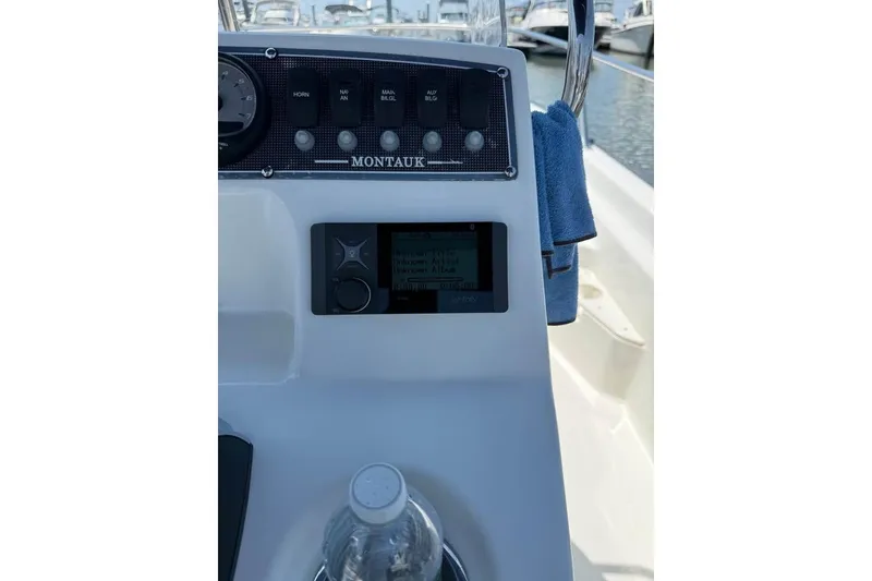 Slide: The Image of 2022 Boston Whaler 170 Montauk dashboard with controls and display, docked at marina. - 6