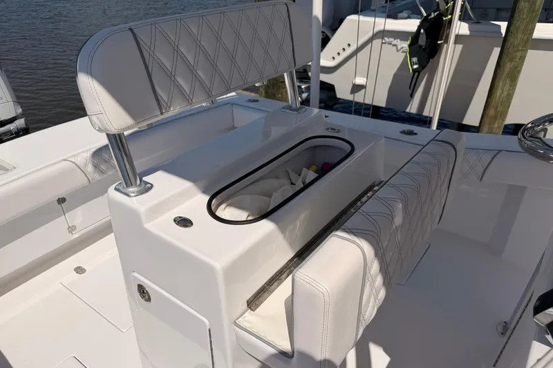 Slide: The Image of 2024 Stoner 23 CC boat interior with white cushioned seating and storage compartment. - 13