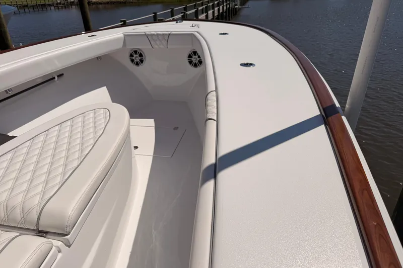 Slide: The Image of 2024 Stoner 23 CC boat interior with white cushioned seating and wood accents. - 16