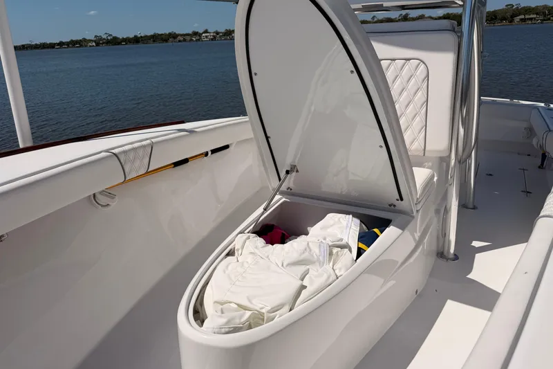 Slide: The Image of 2024 Stoner 23 CC boat with open storage compartment, docked by a serene lake. - 17