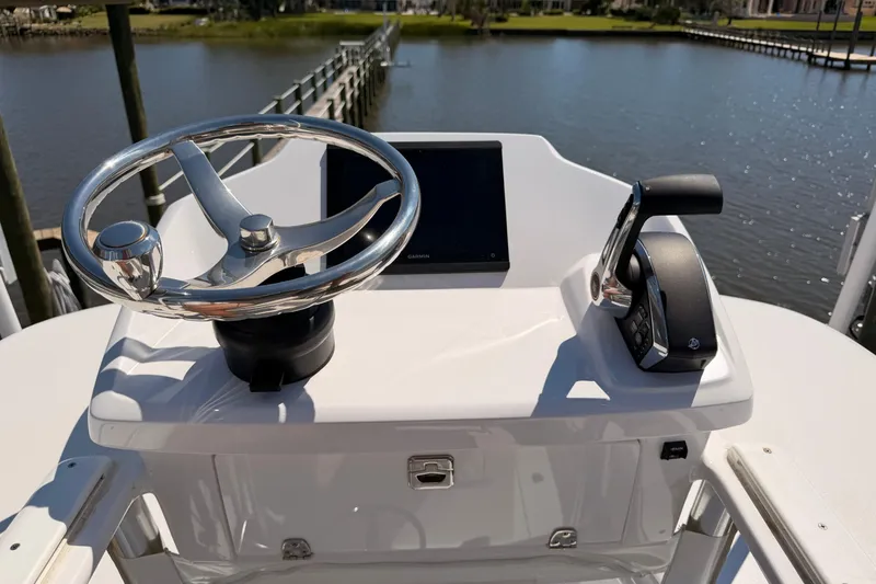 Slide: The Image of 2024 Stoner 23 CC boat helm with steering wheel and control panel by the water. - 22