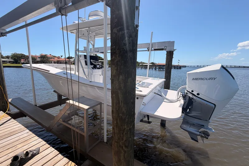 Slide: The Image of 2024 Stoner 23 CC boat with Mercury engine on a lift by the water. - 3