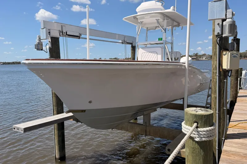 Slide: The Image of 2024 Stoner 23 CC boat on lift by dock, under clear blue sky. - 4