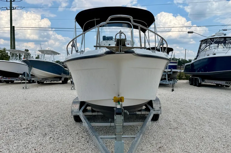 Slide: The Image of 2003 Seaswirl Striper 2101 CC boat on trailer, parked in a gravel lot. - 2