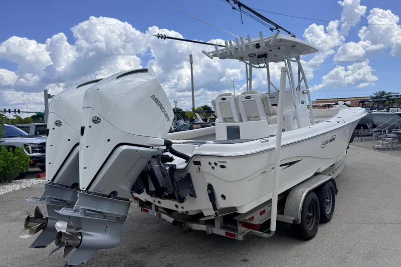 Slide: The Image of 2021 Blue Wave 2800 Makaira boat with dual Mercury engines on a trailer under a cloudy sky. - 7