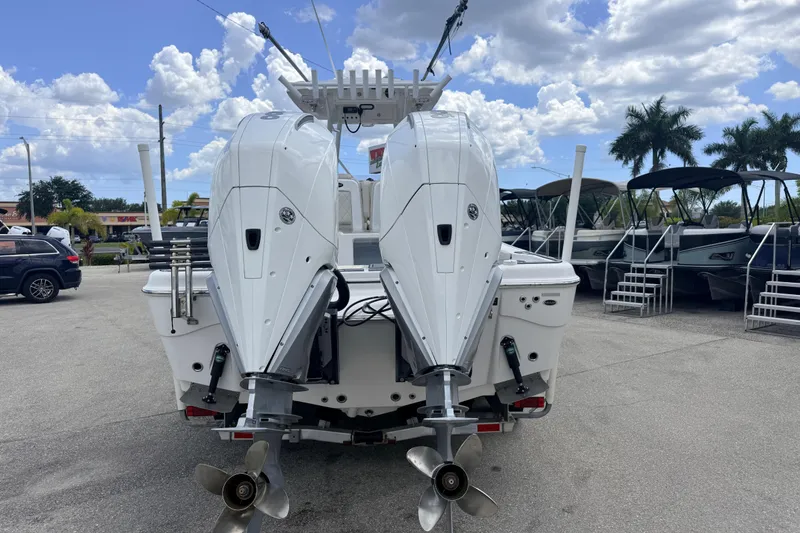 Slide: The Image of 2021 Blue Wave 2800 Makaira boat with dual outboard motors, parked outdoors under a cloudy sky. - 8