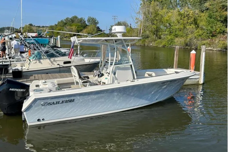 The Image of 2023 Sailfish 220 CC boat docked on a calm river, surrounded by trees. - 0