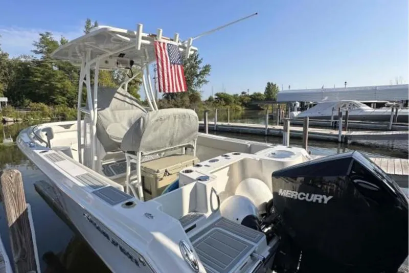 Slide: The Image of 2023 Sailfish 220 CC boat docked, featuring Mercury engine and American flag. - 2