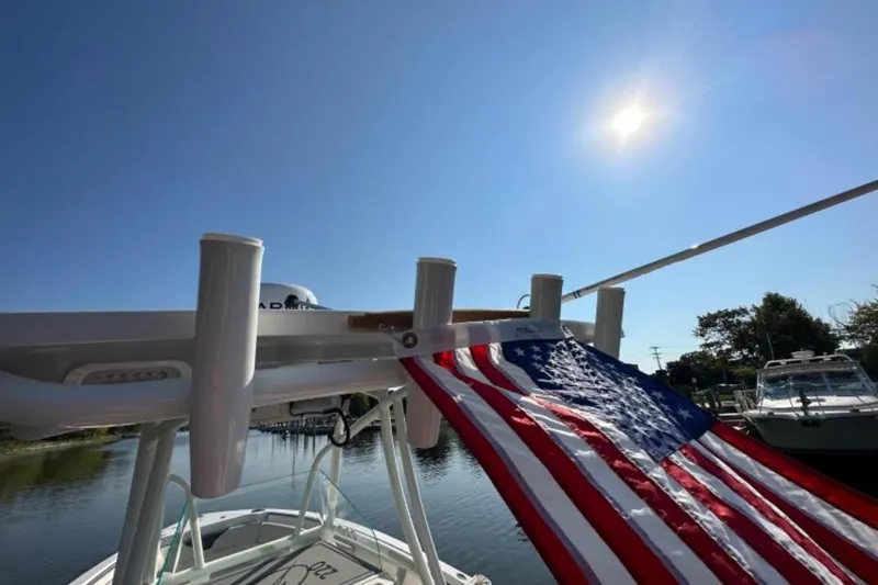 Slide: The Image of 2023 Sailfish 220 CC boat with American flag under clear blue sky. - 3