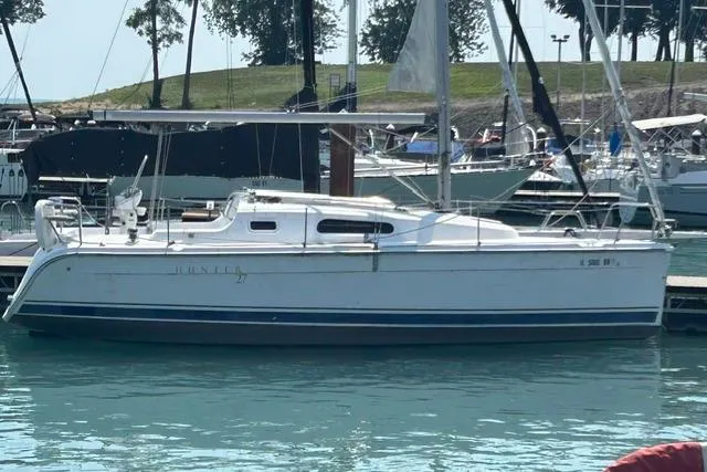 Slide: The Image of 2005 Hunter 27 sailboat docked in a marina, surrounded by other boats. - 2