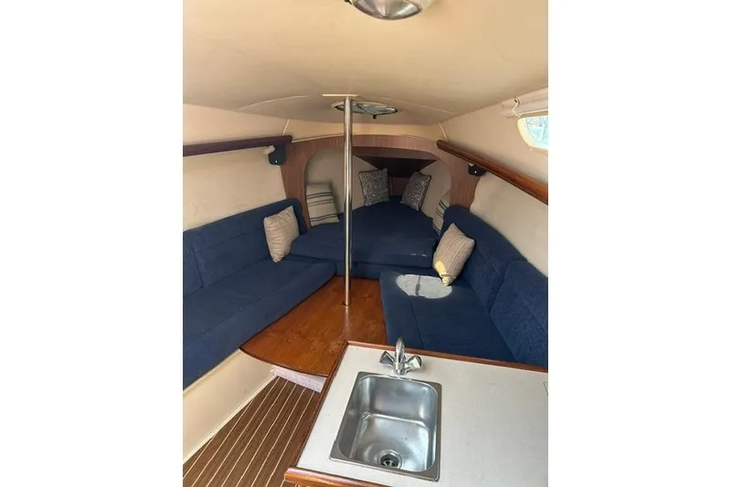 Slide: The Image of Interior of 2005 Hunter 27 sailboat with blue seating and compact kitchenette. - 20