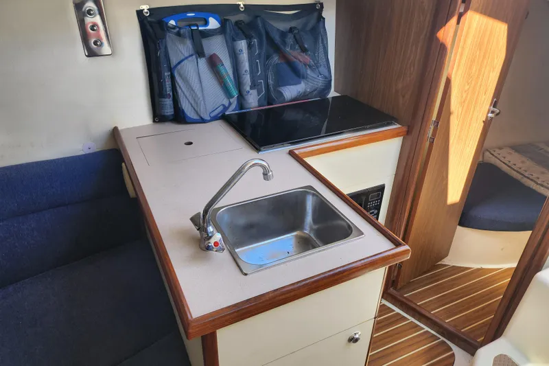 Slide: The Image of Compact kitchen area in a 2005 Hunter 27 sailboat with sink and storage. - 21