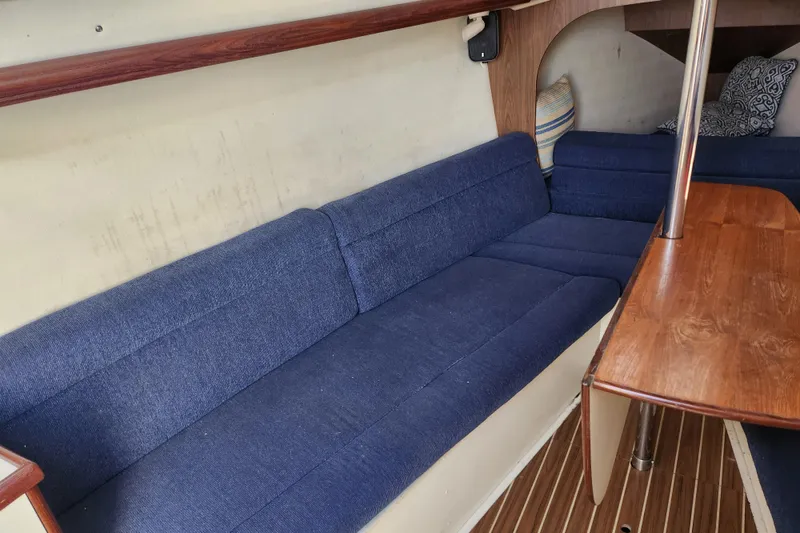 Slide: The Image of Interior of a 2005 Hunter 27 sailboat with blue seating and wooden table. - 25