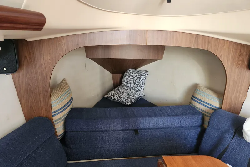 Slide: The Image of Interior cabin of a 2005 Hunter 27 sailboat with blue seating and decorative pillows. - 26