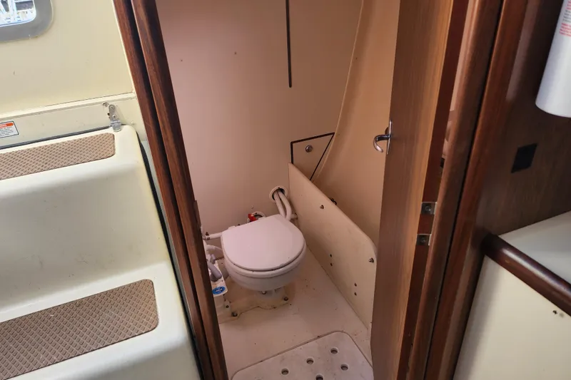 Slide: The Image of Interior view of a 2005 Hunter 27 sailboat bathroom with toilet and wooden door. - 30