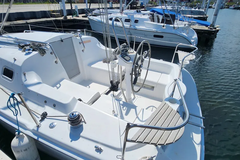 Slide: The Image of 2005 Hunter 27 sailboat docked at marina, featuring spacious cockpit and steering wheel. - 7