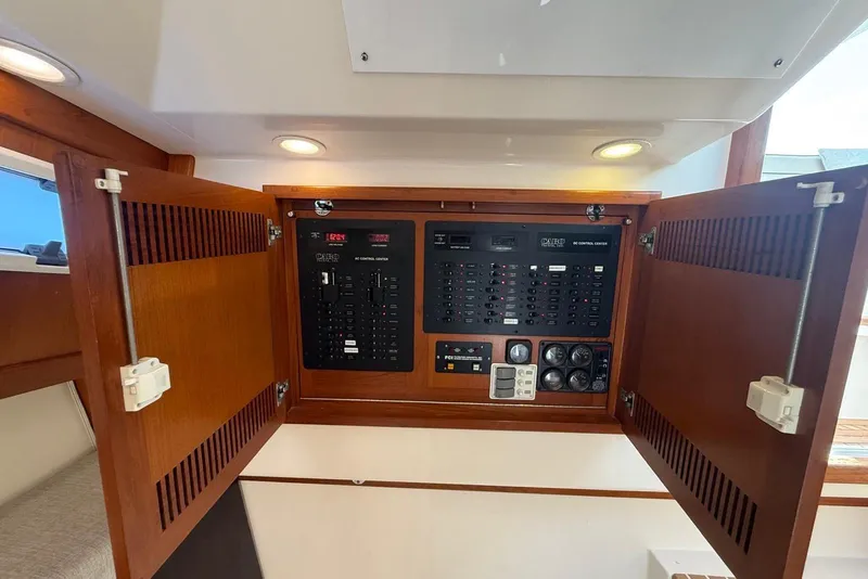 Slide: The Image of Electrical control panel inside a 2003 Cabo 35 Express boat with wooden cabinet doors open. - 21