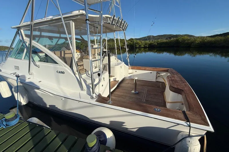 Slide: The Image of 2003 Cabo 35 Express boat docked on calm water, surrounded by lush greenery. - 3