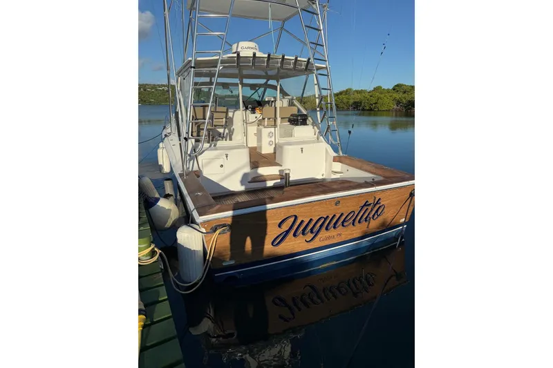 Slide: The Image of 2003 Cabo 35 Express boat docked, featuring "Juguetito" on the stern. - 4