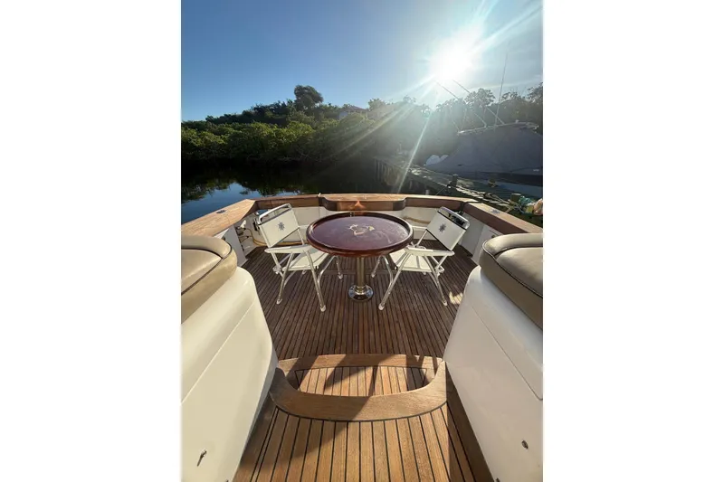 Slide: The Image of 2003 Cabo 35 Express yacht deck with seating and table under bright sunlight. - 8
