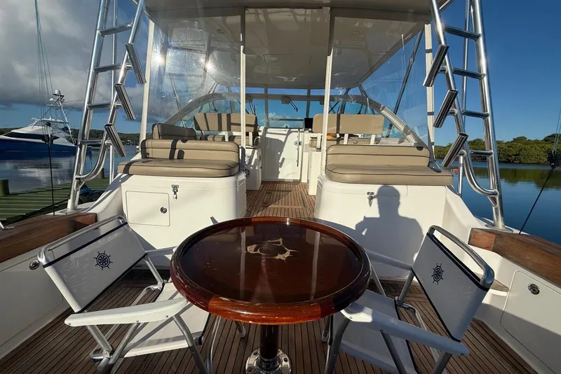 Slide: The Image of 2003 Cabo 35 Express yacht interior with seating, table, and ladders on a sunny day. - 9