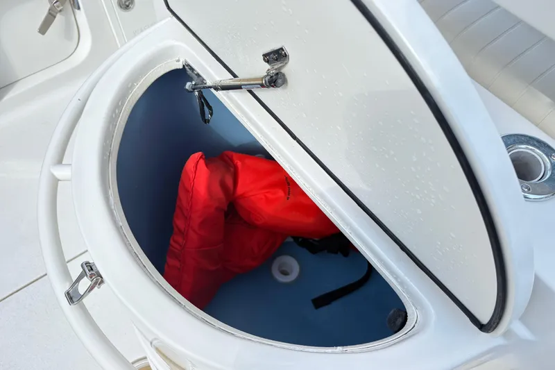 Slide: The Image of Open storage compartment on 2017 Carolina Skiff Sea Chaser 27 HFC with red life jacket. - 13