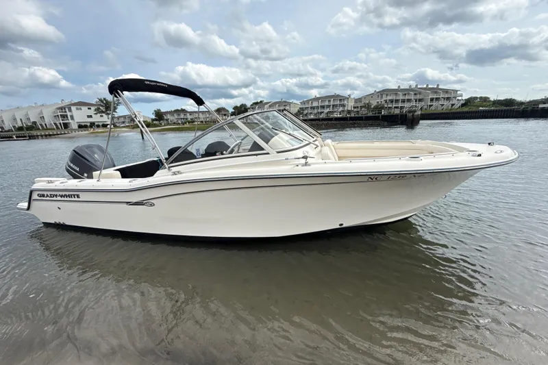 Slide: The Image of 2017 Grady-White Freedom 235 boat on calm water, with scenic waterfront background. - 6