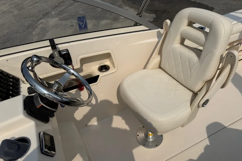 Slide: The Image of 2017 Grady-White Freedom 235 boat helm with steering wheel and cushioned captain's chair. - 64