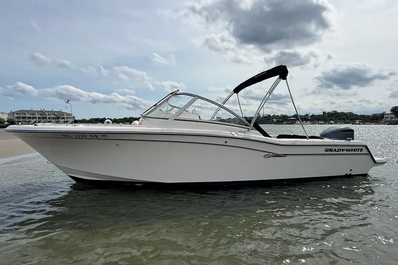 Slide: The Image of 2017 Grady-White Freedom 235 boat on calm water, featuring sleek design and bimini top. - 7