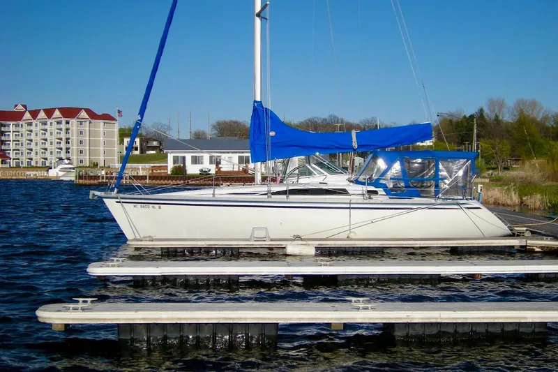 The Image of 1987 Hunter Legend 35 sailboat docked with blue sails and clear sky background. - 0