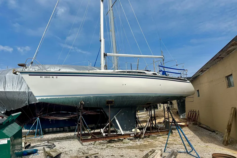 Slide: The Image of 1987 Hunter Legend 35 sailboat on dry dock, ready for maintenance under clear blue sky. - 2