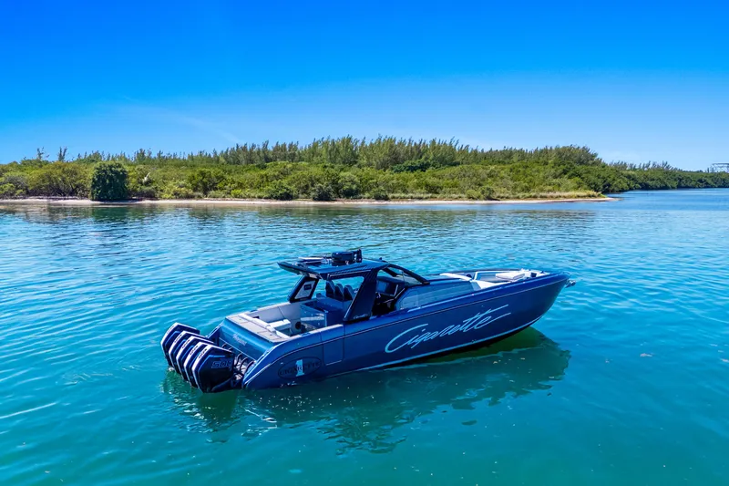 Slide: The Image of 2024 Cigarette 42' Auroris boat on calm blue water near a lush shoreline. - 2
