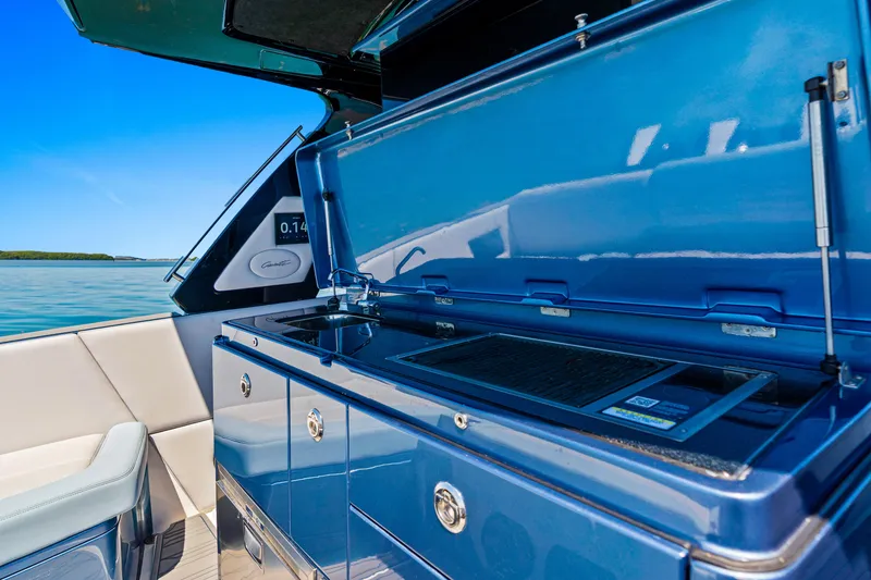 Slide: The Image of Outdoor kitchen on 2024 Cigarette 42' Auroris boat with blue cabinetry and scenic water view. - 21