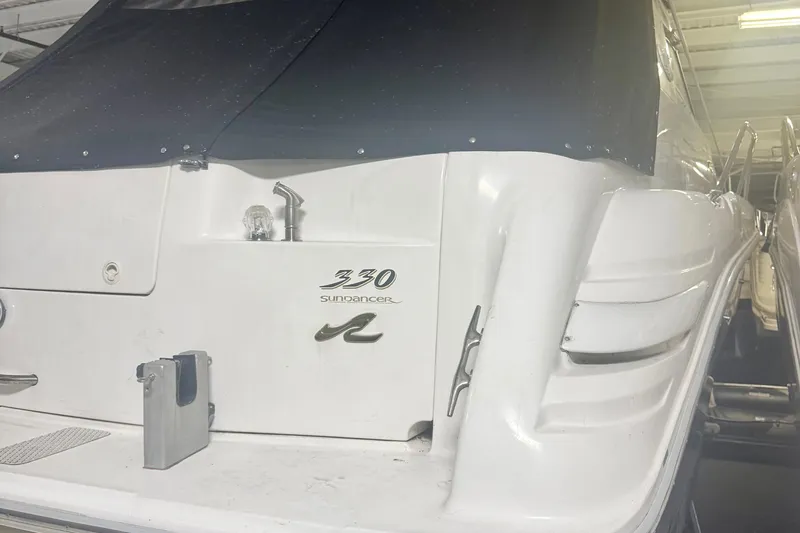 Slide: The Image of 1996 Sea Ray 330 Sundancer boat with white exterior and black canopy in storage. - 15