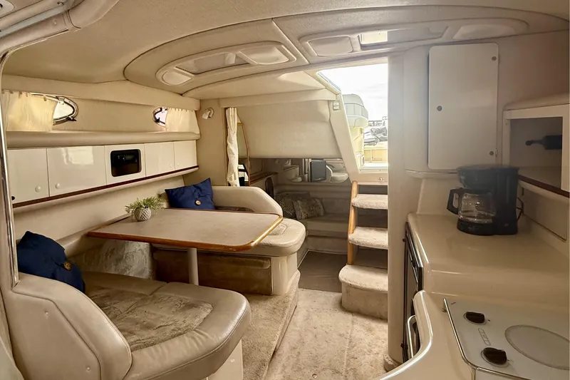 Slide: The Image of Interior of a 1996 Sea Ray boat featuring a cozy dining area and kitchenette. - 25
