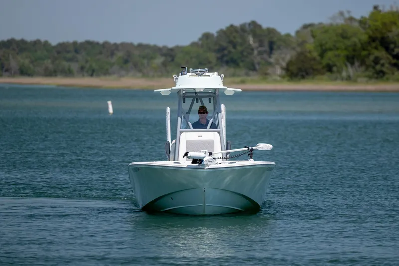 Slide: The Image of 2022 ZCB Freemason 26 boat cruising on a serene lake with lush green shoreline. - 10