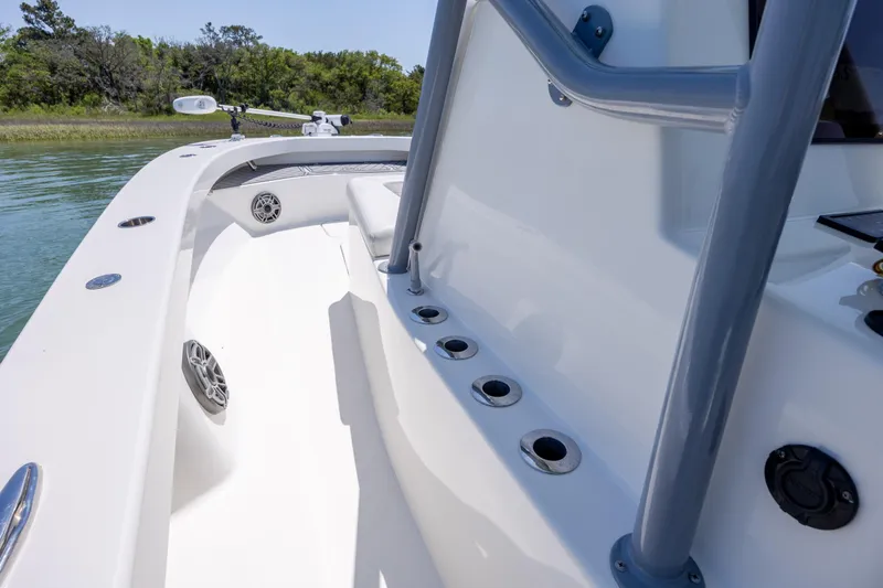 Slide: The Image of 2022 ZCB Freemason 26 boat interior with rod holders and speakers on a calm waterway. - 30